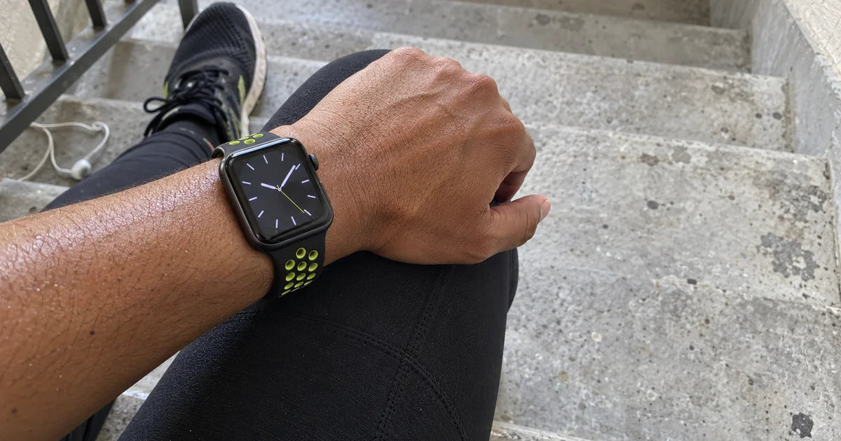 Apple Watch cu o curea de ceas sport din silicon perforat, neagră și verde fluorescent, în timpul unei alergări
