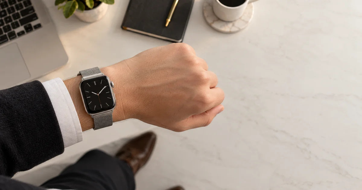 Apple Watch mit einem silberfarbenen Mailänder Armband und seinem Magnetverschluss, Nahaufnahme am Handgelenk